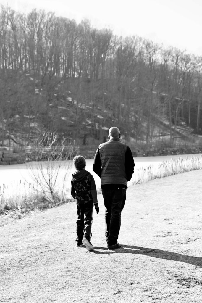 black and white photo of a man and his son walking along a path beside the pond at earl bales park during covid-19 spring 2021