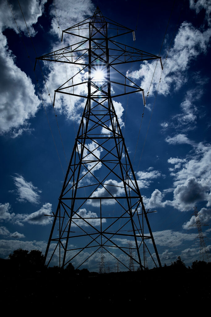 tall hydro tower against clouds on a bright day