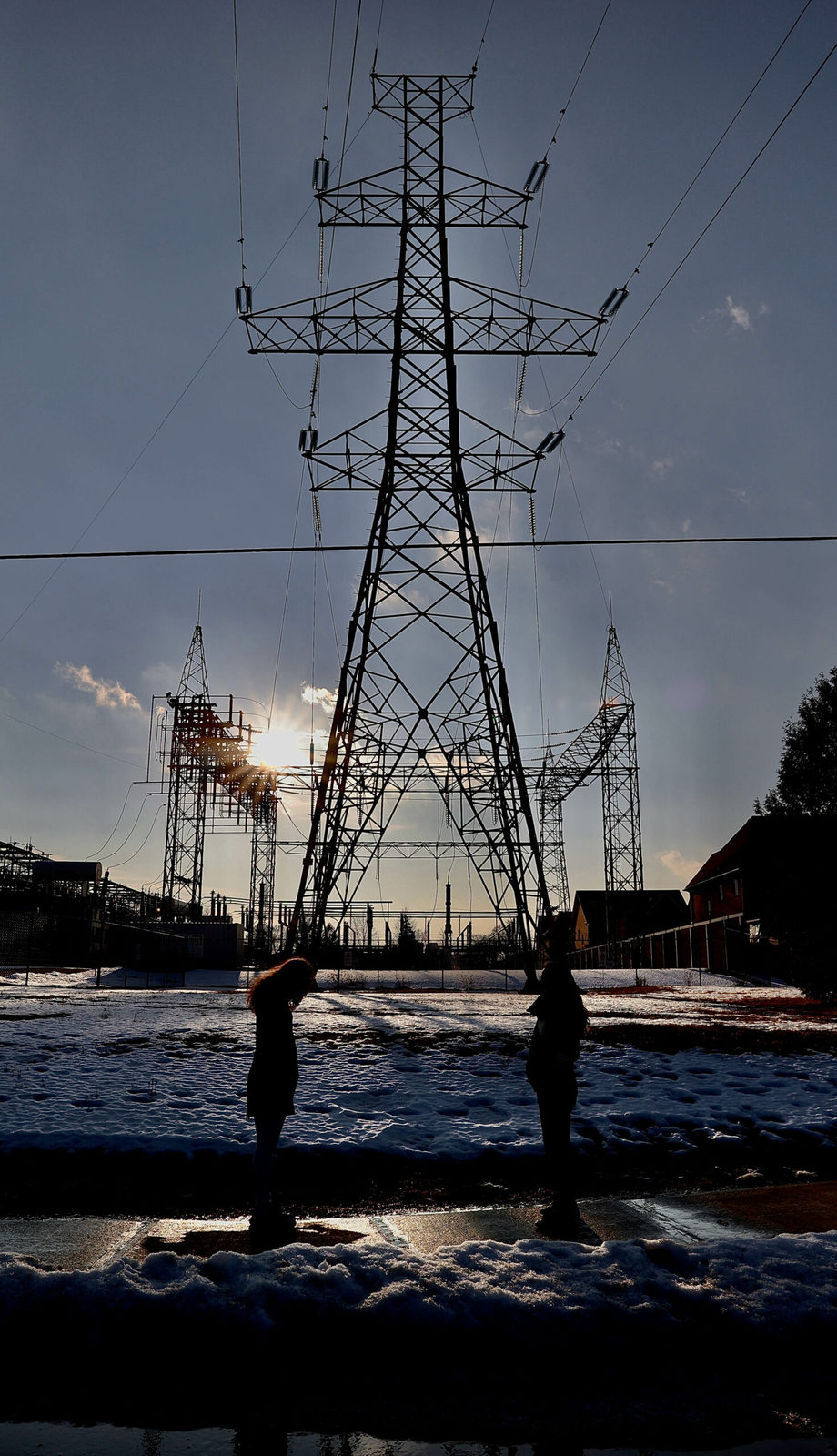 colour photo of two masked, young women talking in front of the hydro tower in the late-day sun on maxwell road in north, york, canada